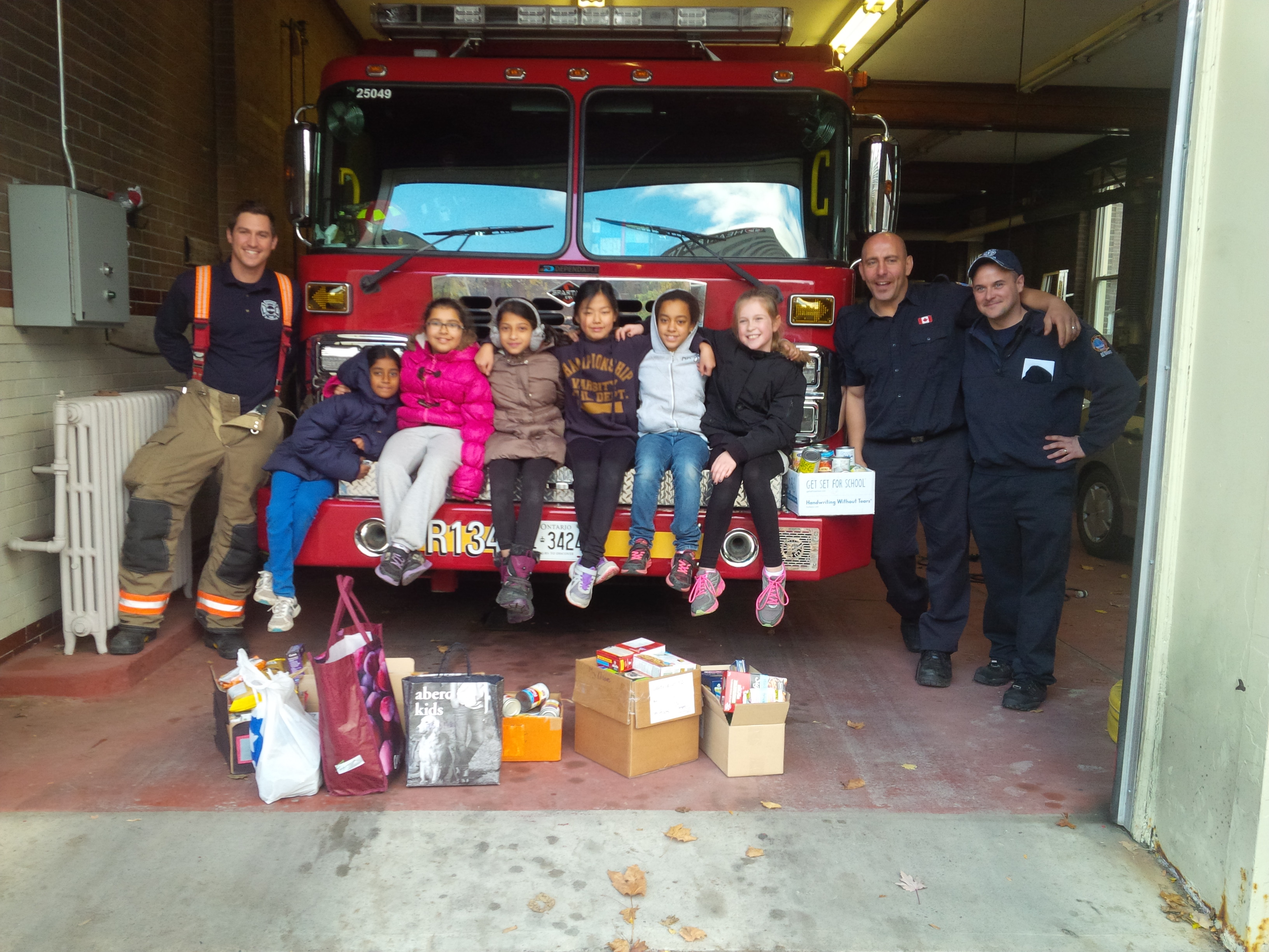 Members of the Me to We Club at the fire station with our food drive donation and the firefighters.