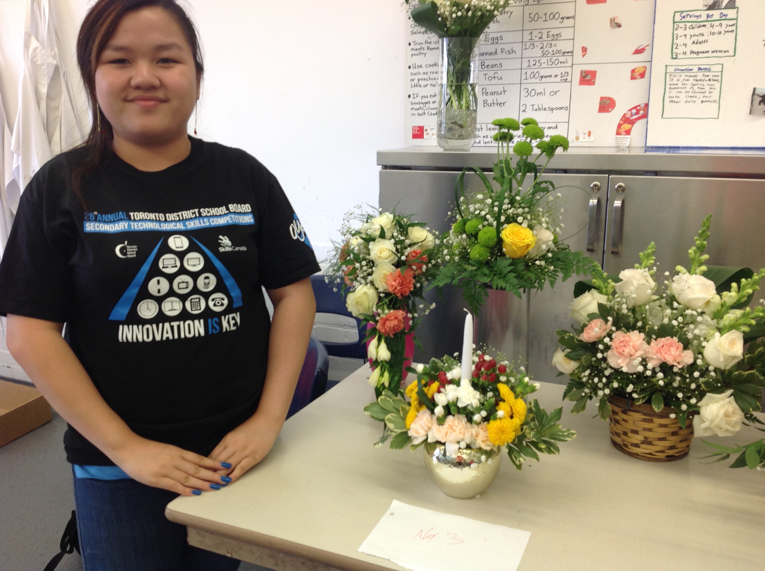 student beside floral arrangements
