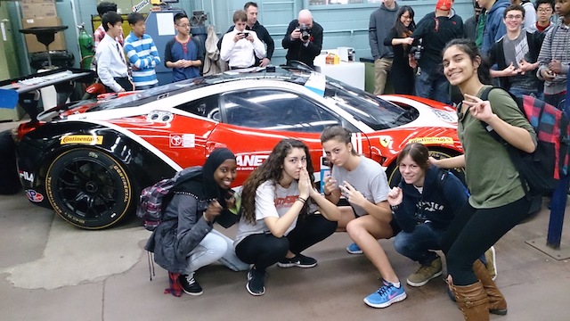 group of students take picture infrot of car
