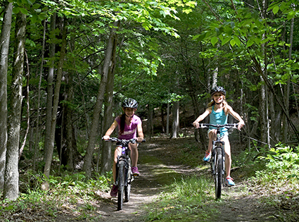 2 Girls riding bikes on trail path