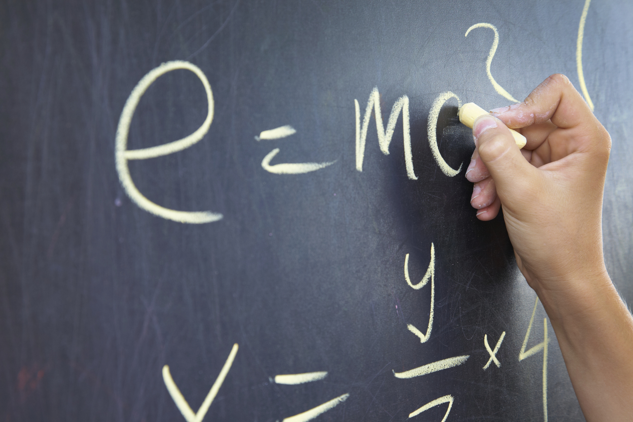 closeup of blackboard with a hand writing the formula e=mc2 Open Gallery