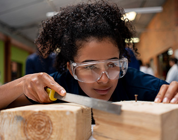 A high school student busily chisels a block of wood