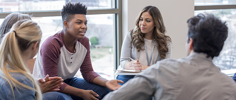 A content high school student in engaged in an interview with several other people who calmly listen