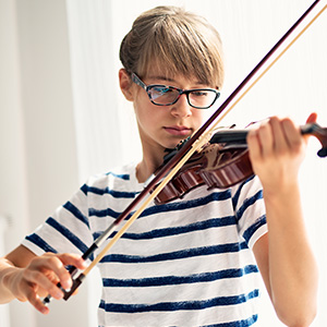 A middle school aged student concentrates as she plays the violin