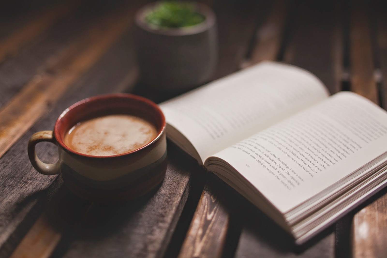 An image of a coffee filled mug next to a book