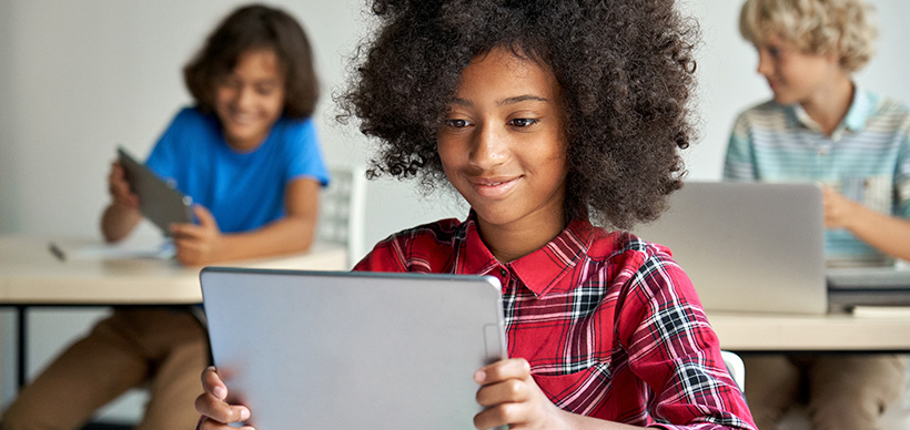 A classroom featuring three middle-school aged students happily gazing at their personal mobile devices