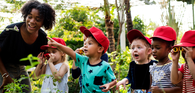 A female teacher joins in her young students enthusiasm at discovering greenhouse wonders