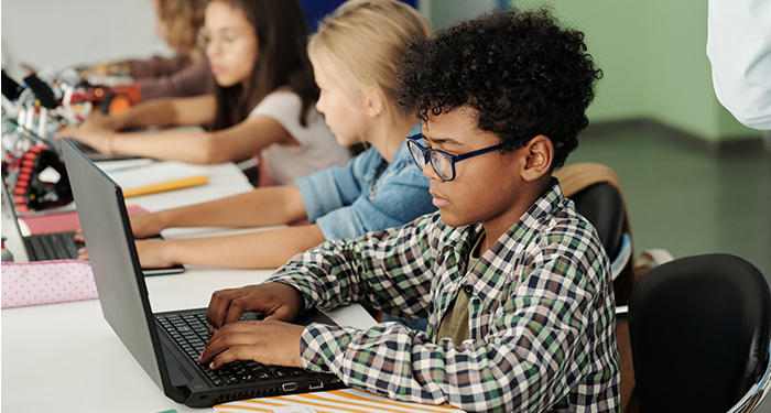 A young bespectacled middle schooler concentrates as he works at his computer