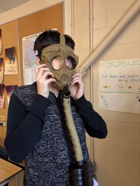 Student trying on World War 1 gas mask.