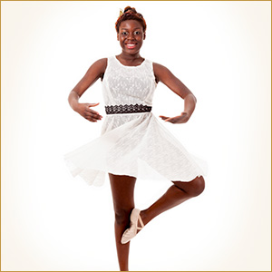 A tween aged female student strikes a ballerina pose in her flowing white tutu