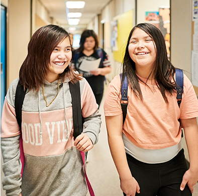 On their way to class, two students smile while in each other's company