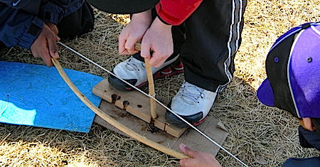 Students attempting to get an ember with a bow and drill