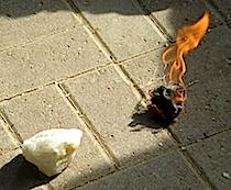 A nest of natural fibre on fire and a piece of quartz rock used to create sparks to light a fire